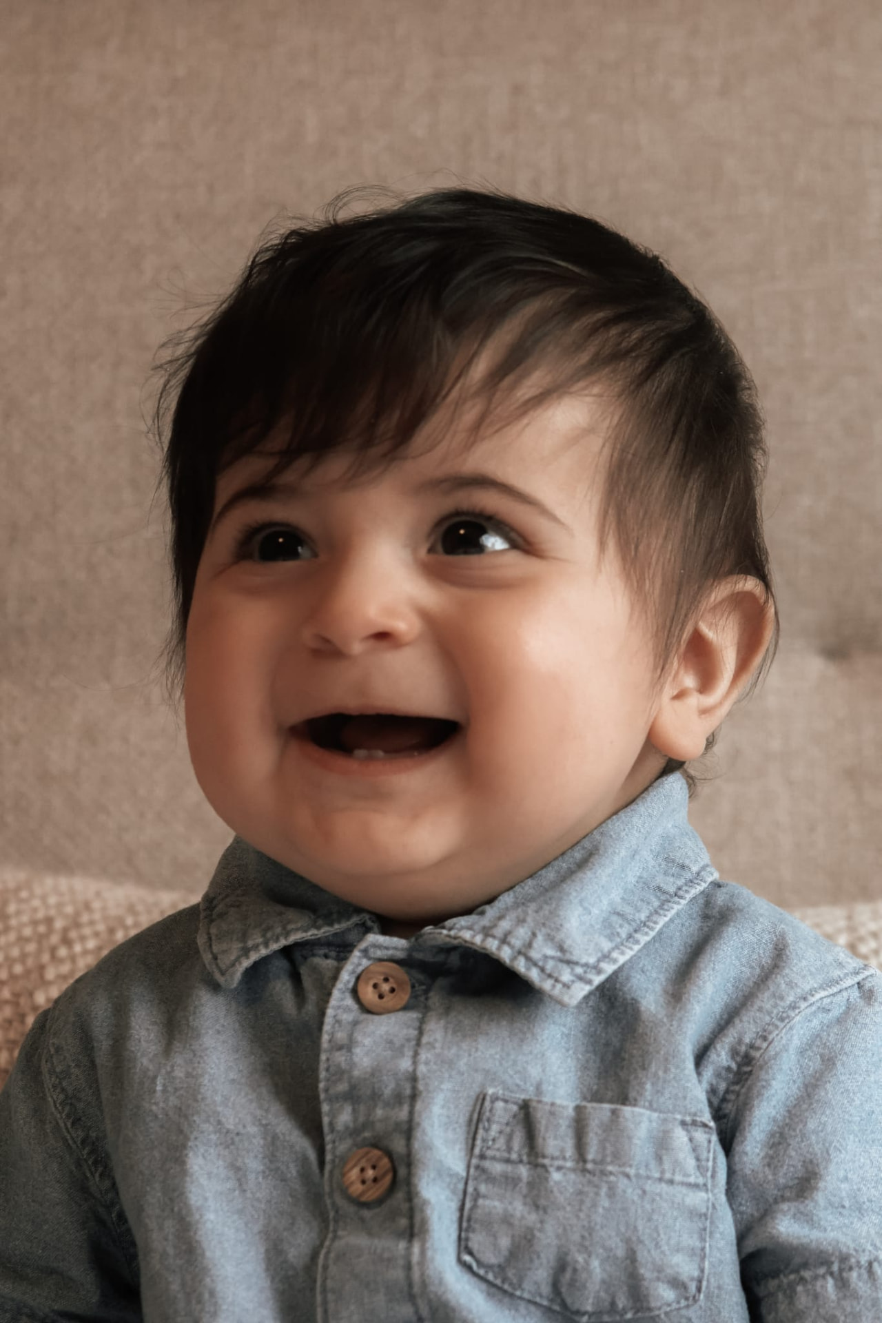 Smiling baby in a denim shirt at home