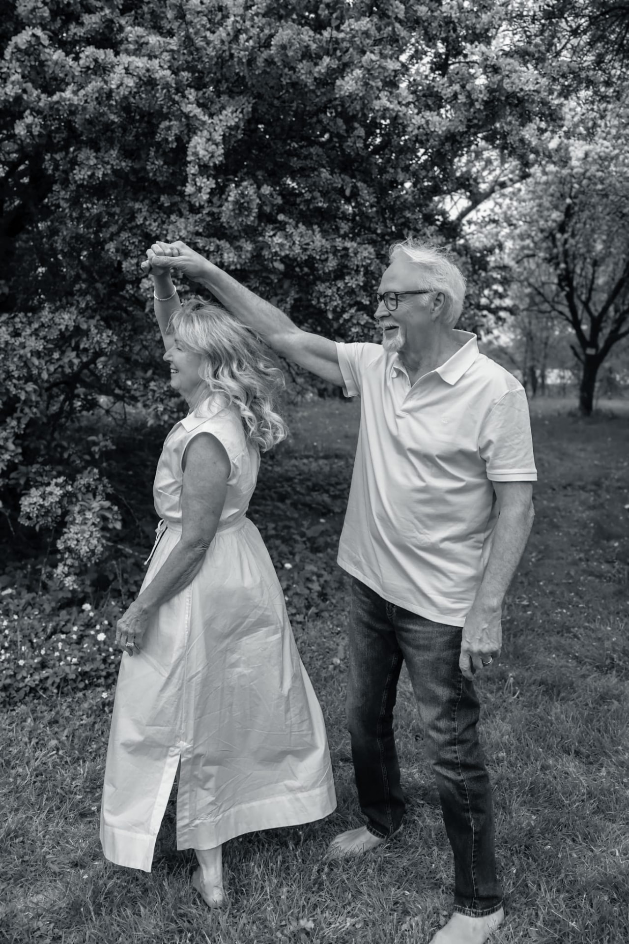Black and white photo of a couple dancing in an orchard
